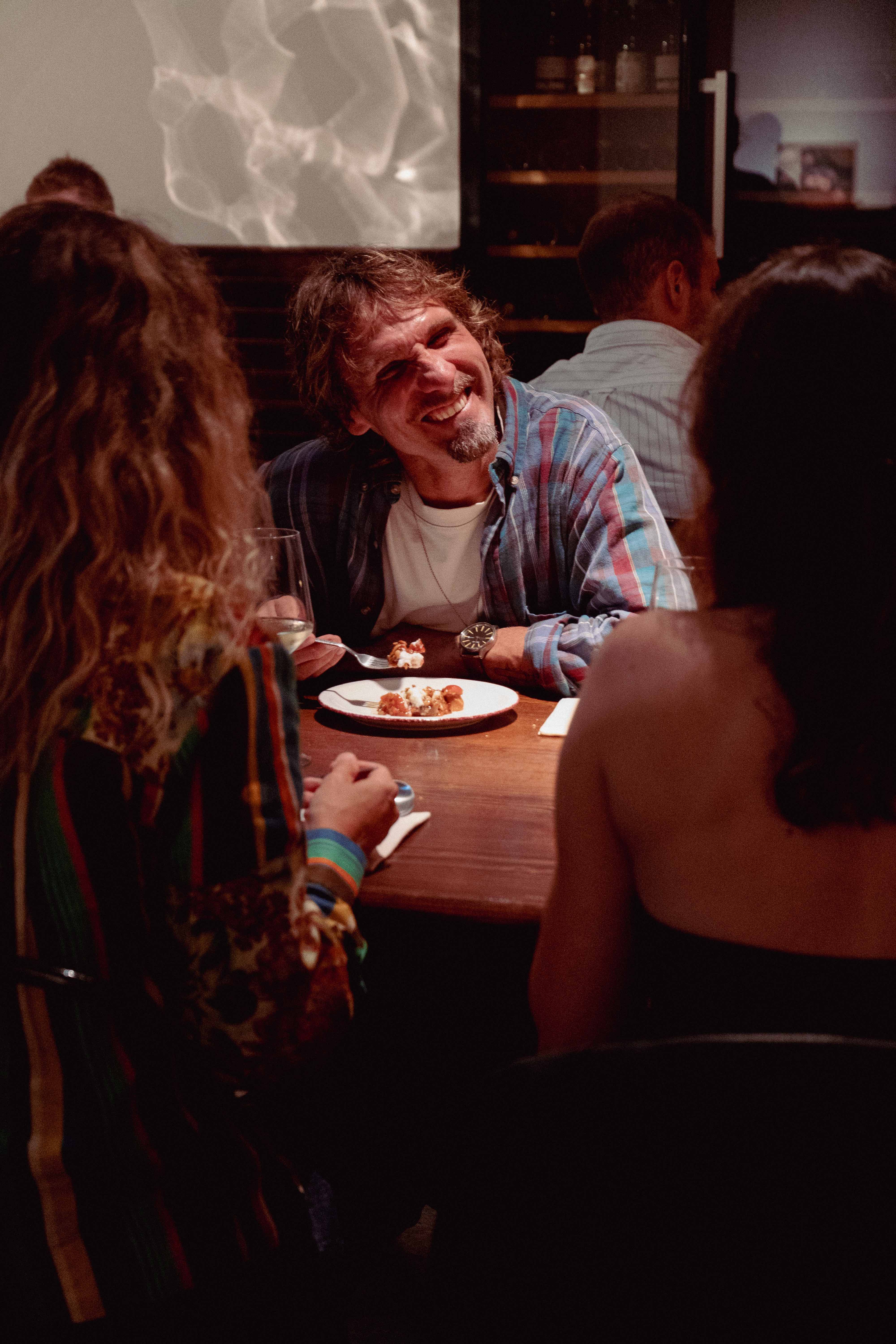 Personas compartiendo una comida en Oltre, en una atmósfera cálida y social.