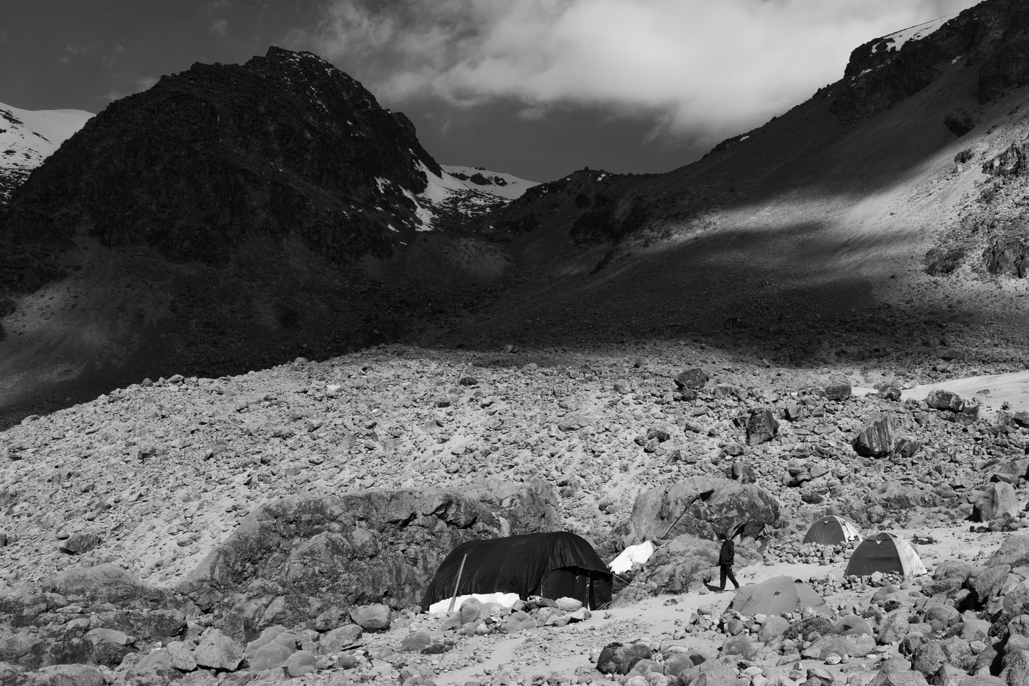 High altitude base camp with tents among rocky terrain and mountain clouds