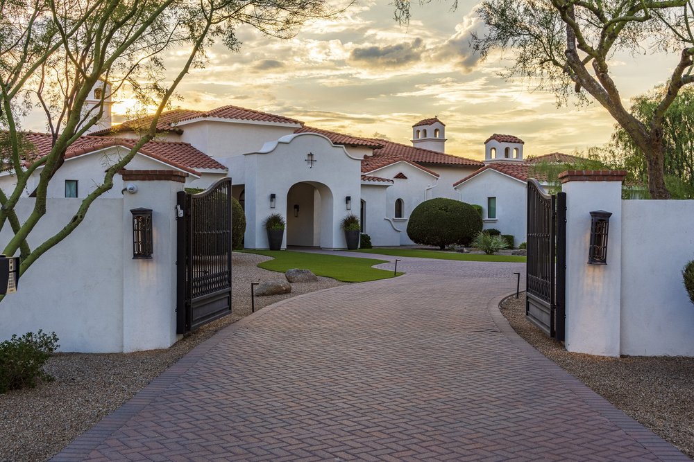 Gated brick paver entry drive with wrought-iron gates at sunset