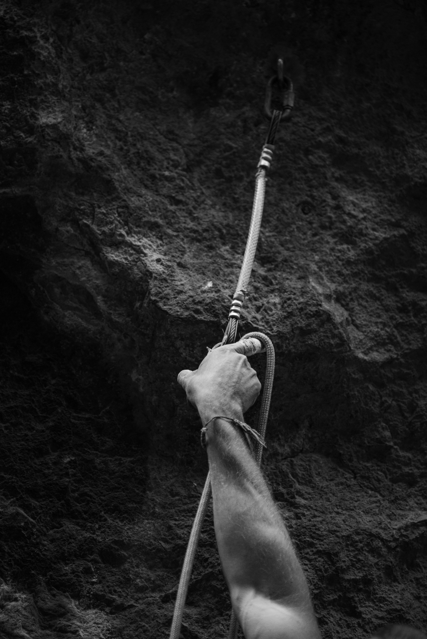 Climber's hand reaching for rope against dark rock