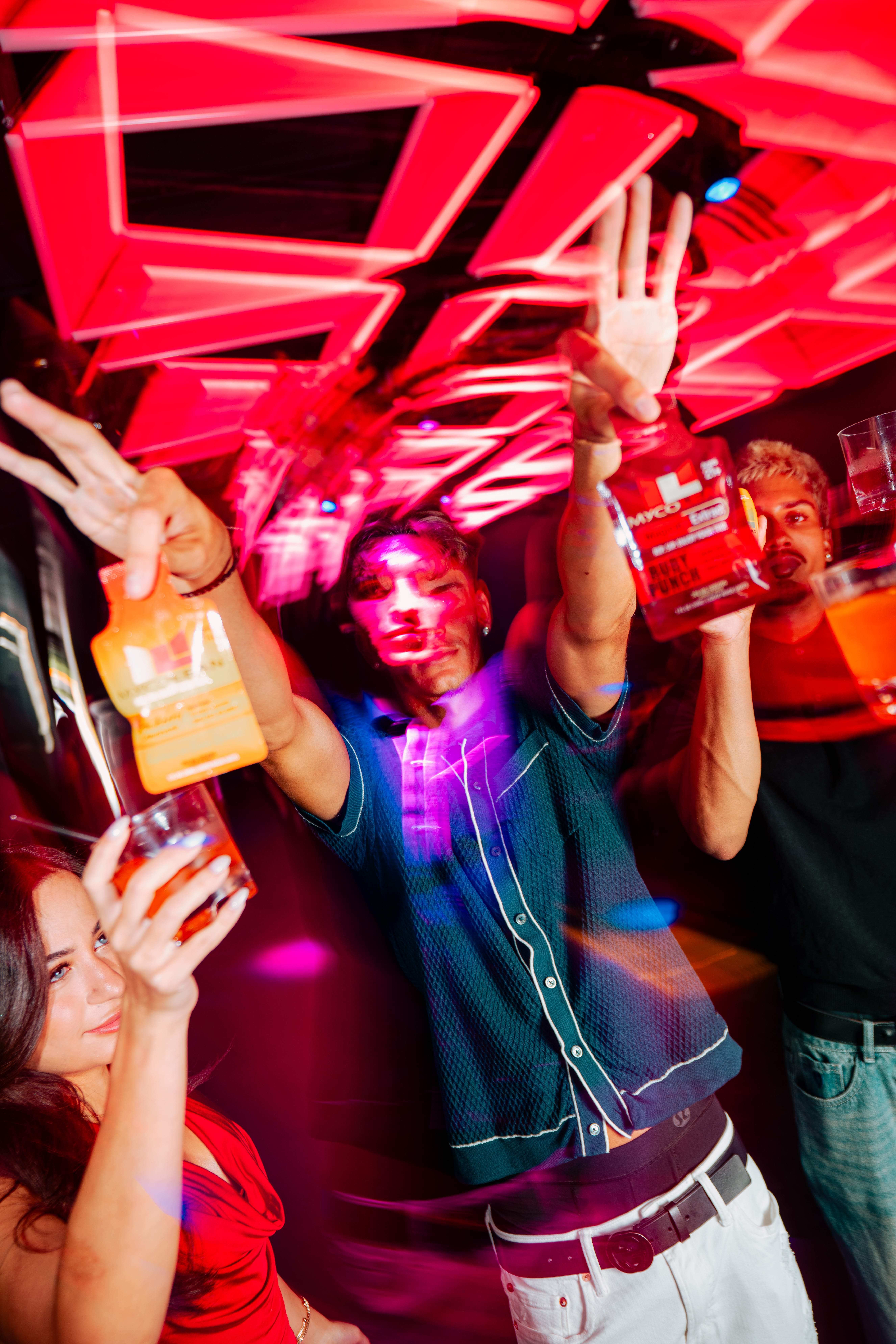 Nightlife crowd with branded drinks under neon