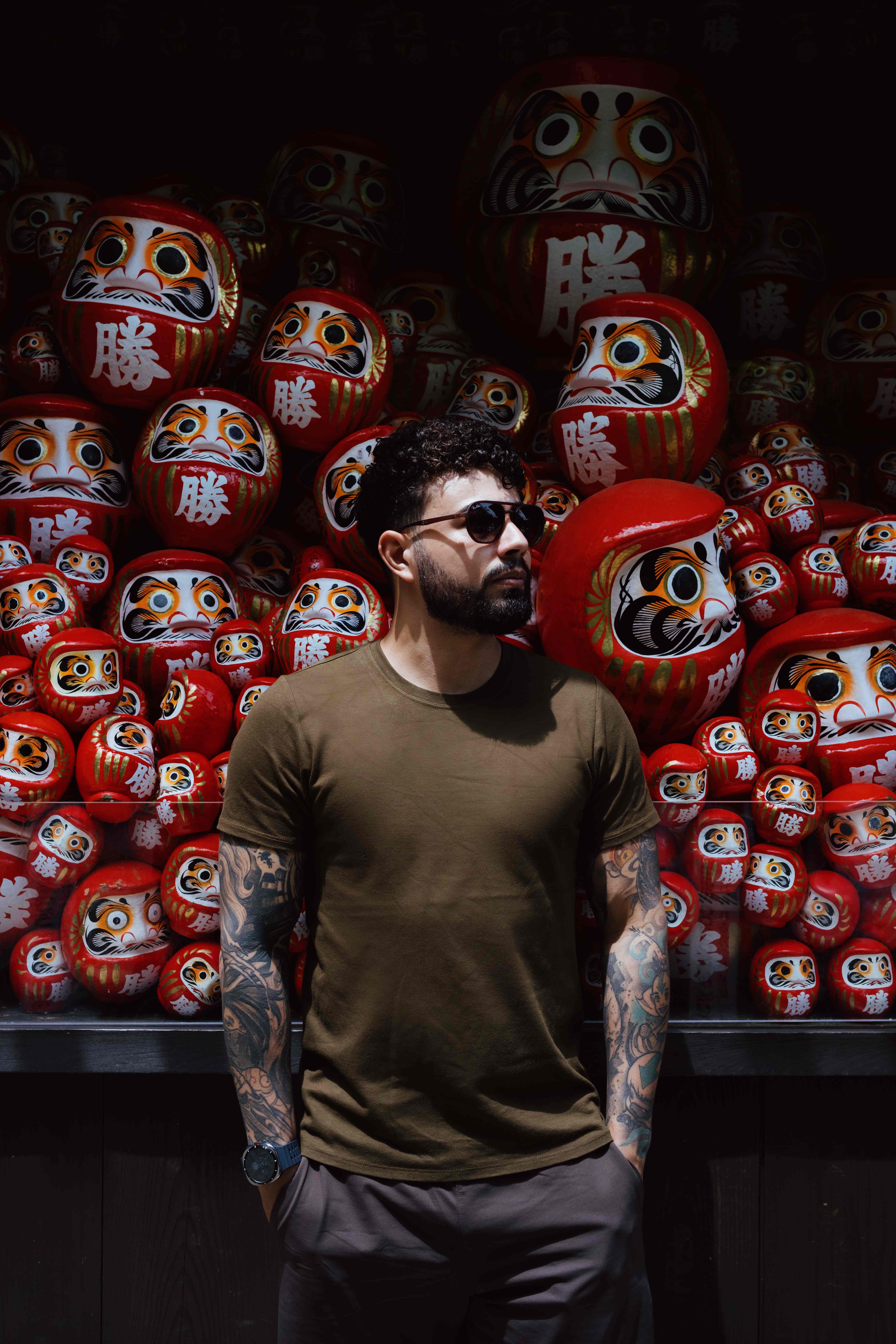 Standing in front of a wall of red daruma dolls