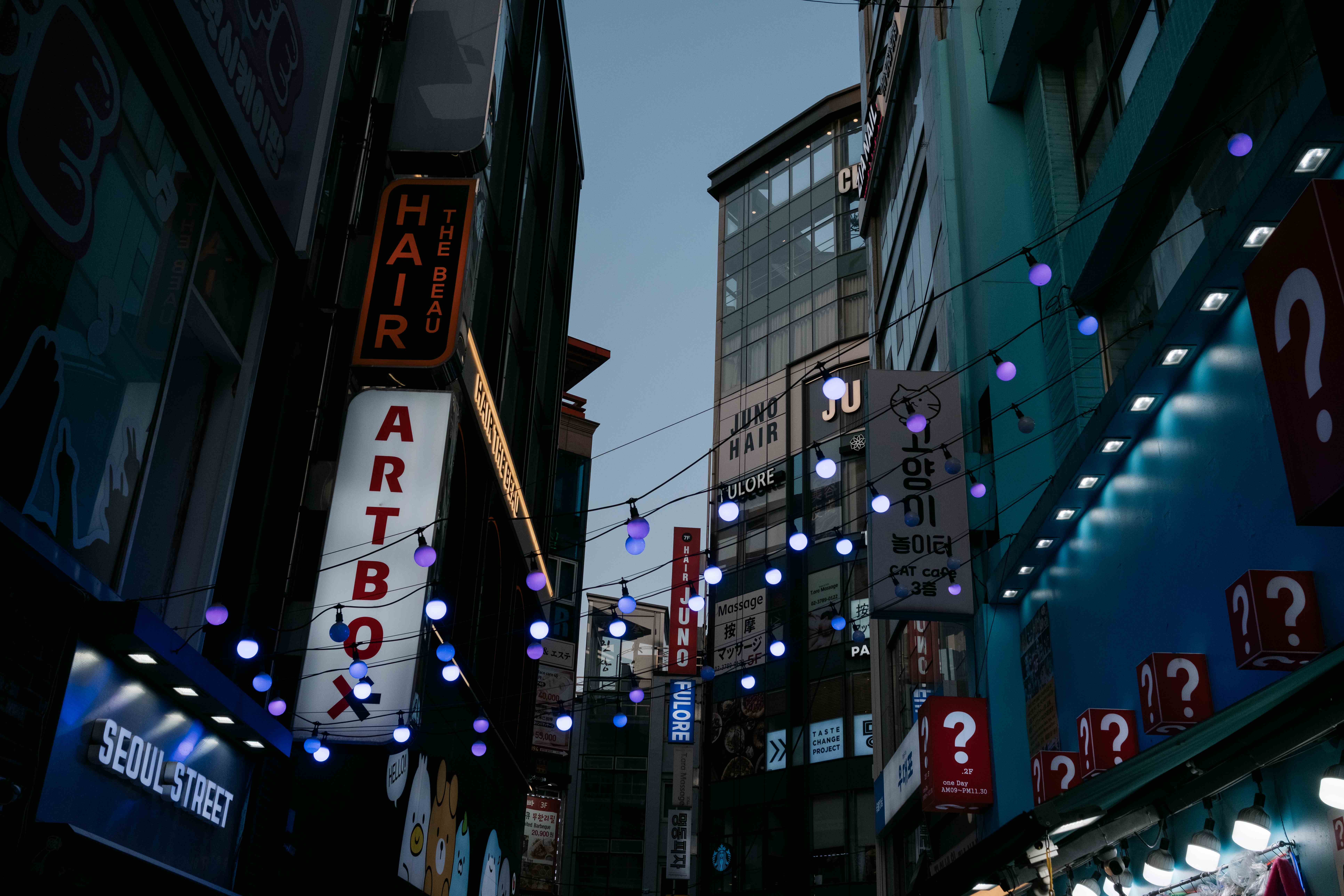 Seoul street at dusk with string lights and neon signs