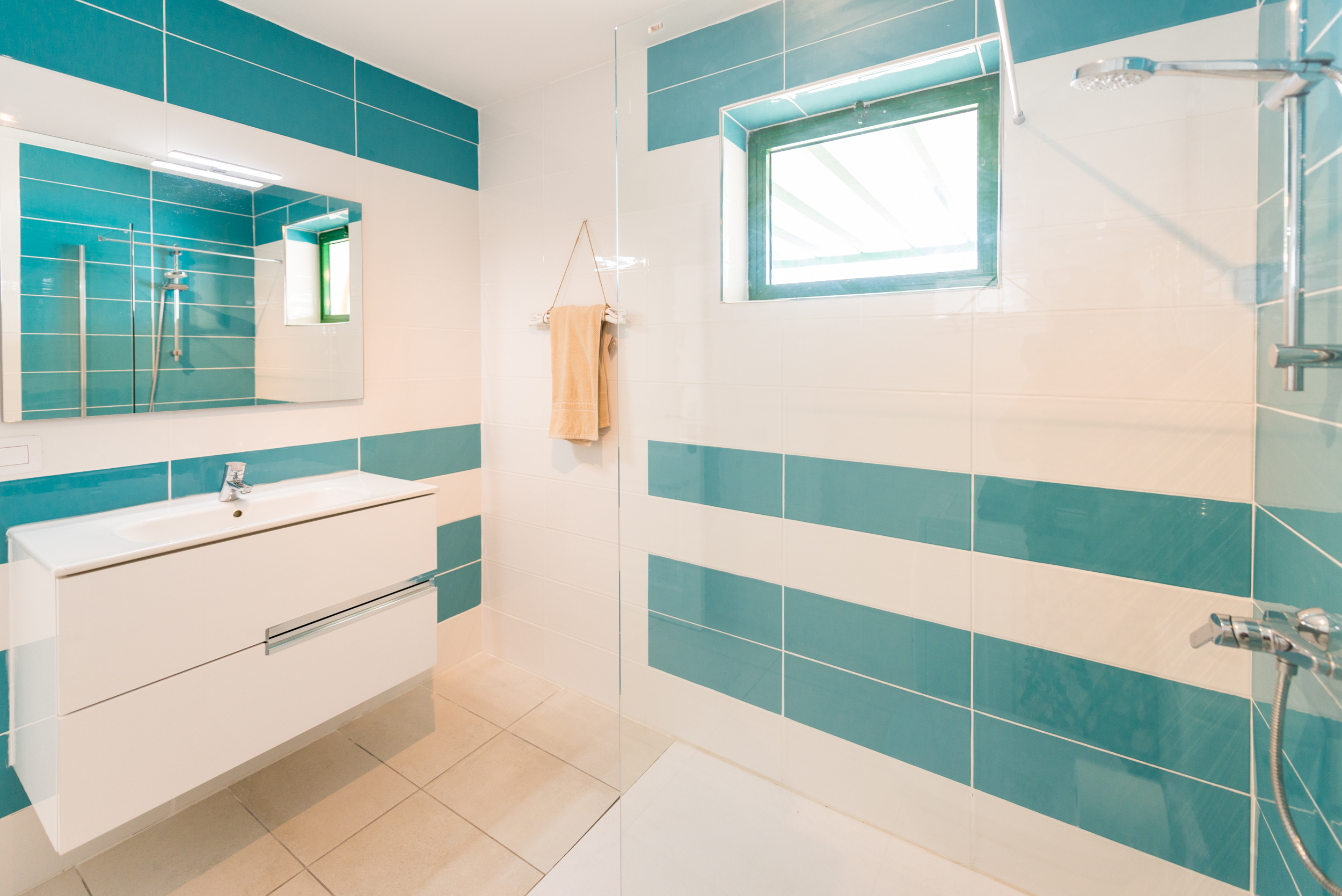 Bathroom with teal and white striped tiles and walk-in shower