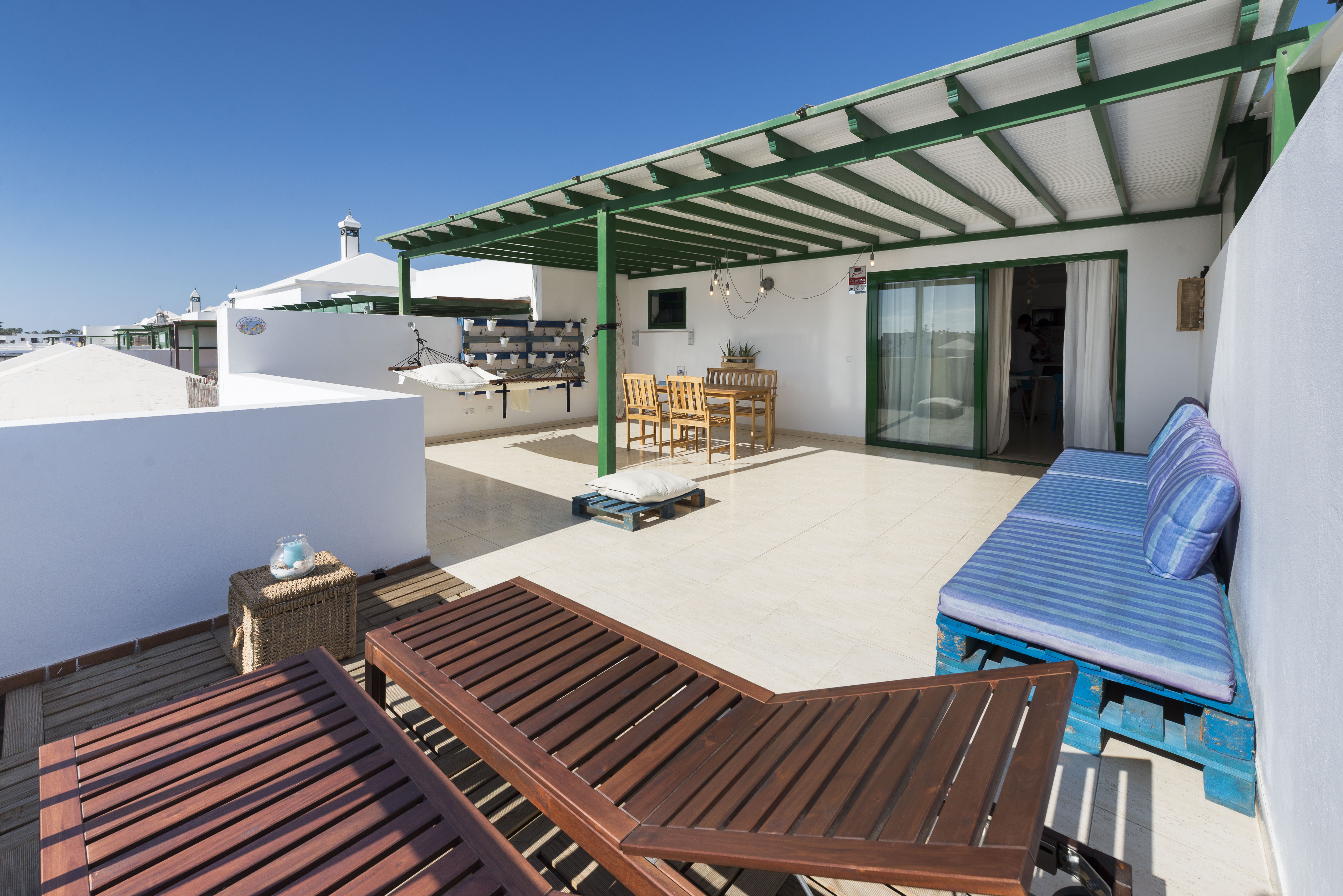 Rooftop terrace with sun loungers, hammock, blue sofa and green pergola
