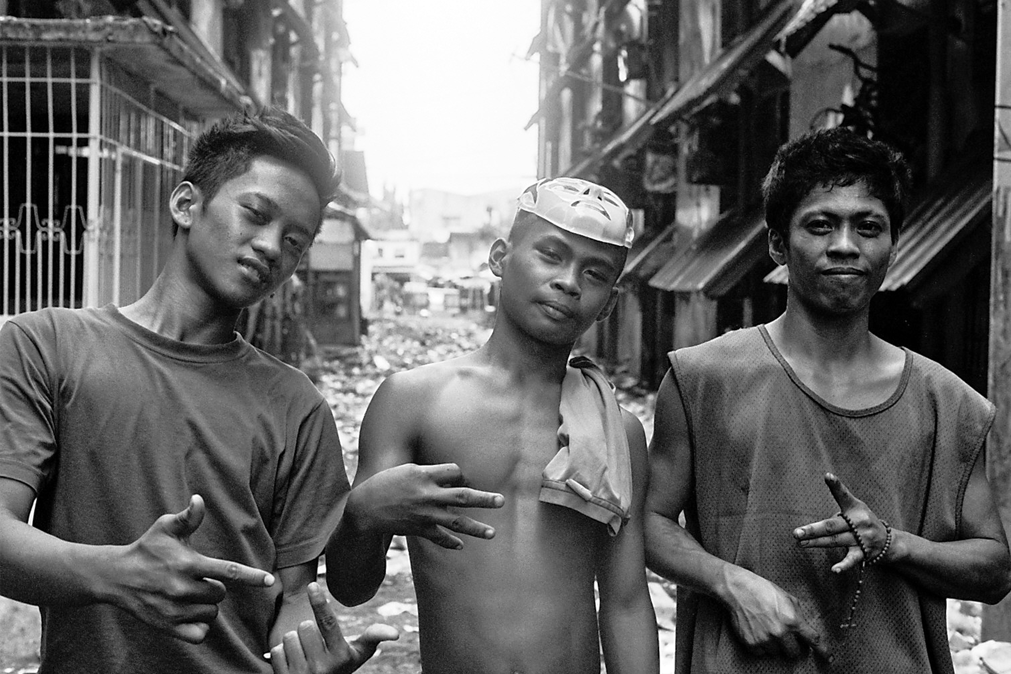 Three young men standing in urban alley wearing casual t-shirts with casual relaxed poses