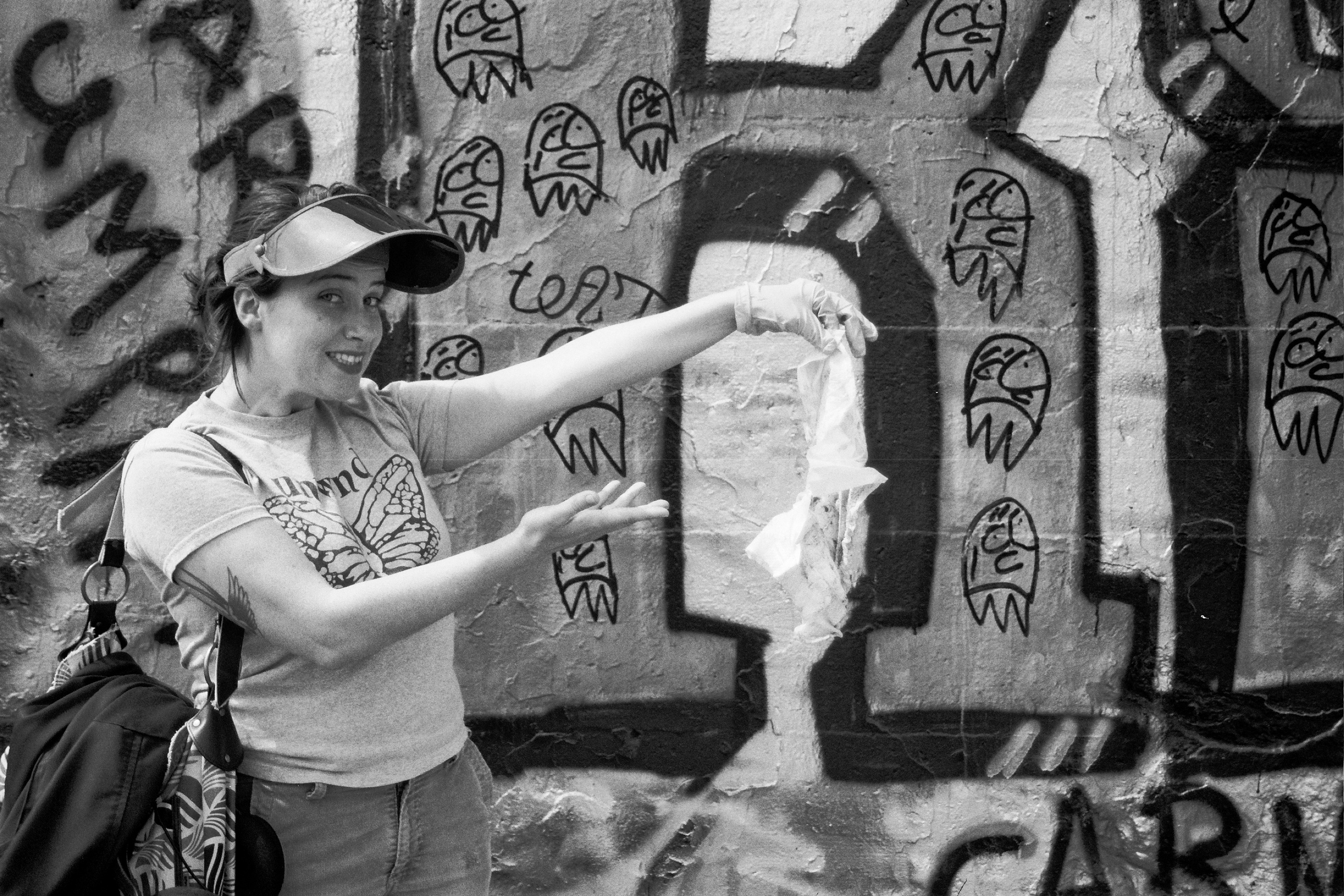 Woman in visor pointing at decorative street graffiti and artistic murals on concrete wall