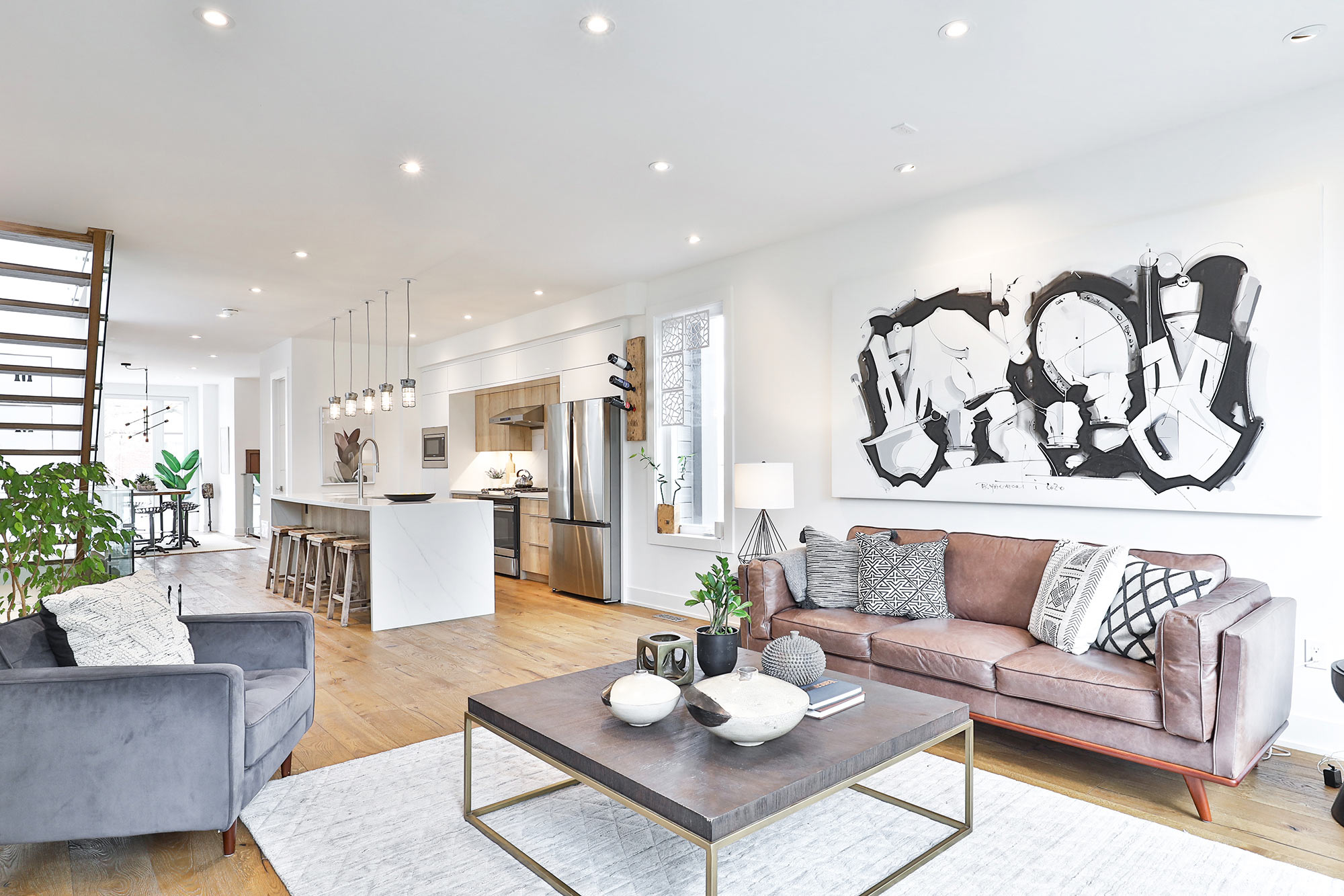 Open-concept living and kitchen with leather sofa and abstract art