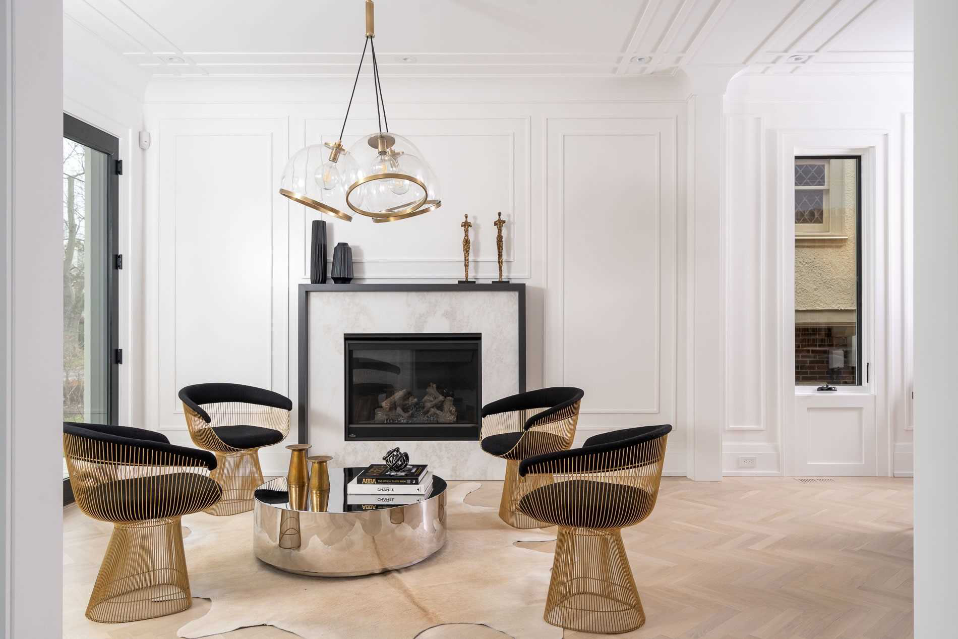 Bright white living room with gold wire chairs and a marble fireplace