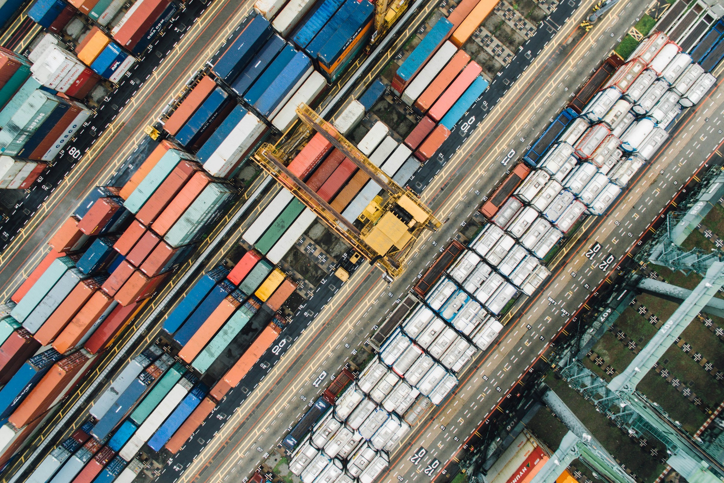 Aerial view of colorful shipping containers at port with yellow crane