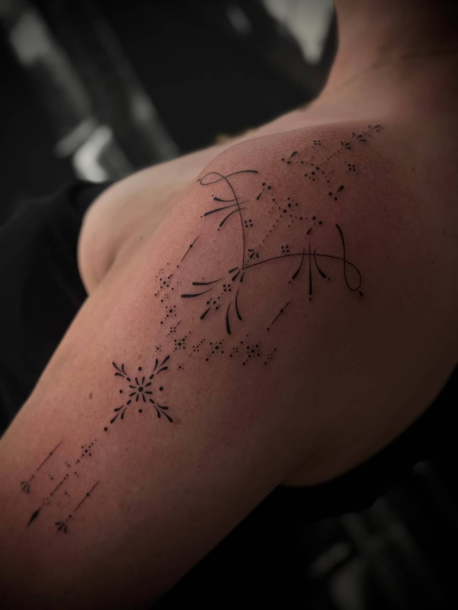Fineline Schulter-Tattoo mit Sternbild und ornamentalen Details