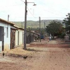 Rote Sandstraße mit einfachen Häusern und Hügeln