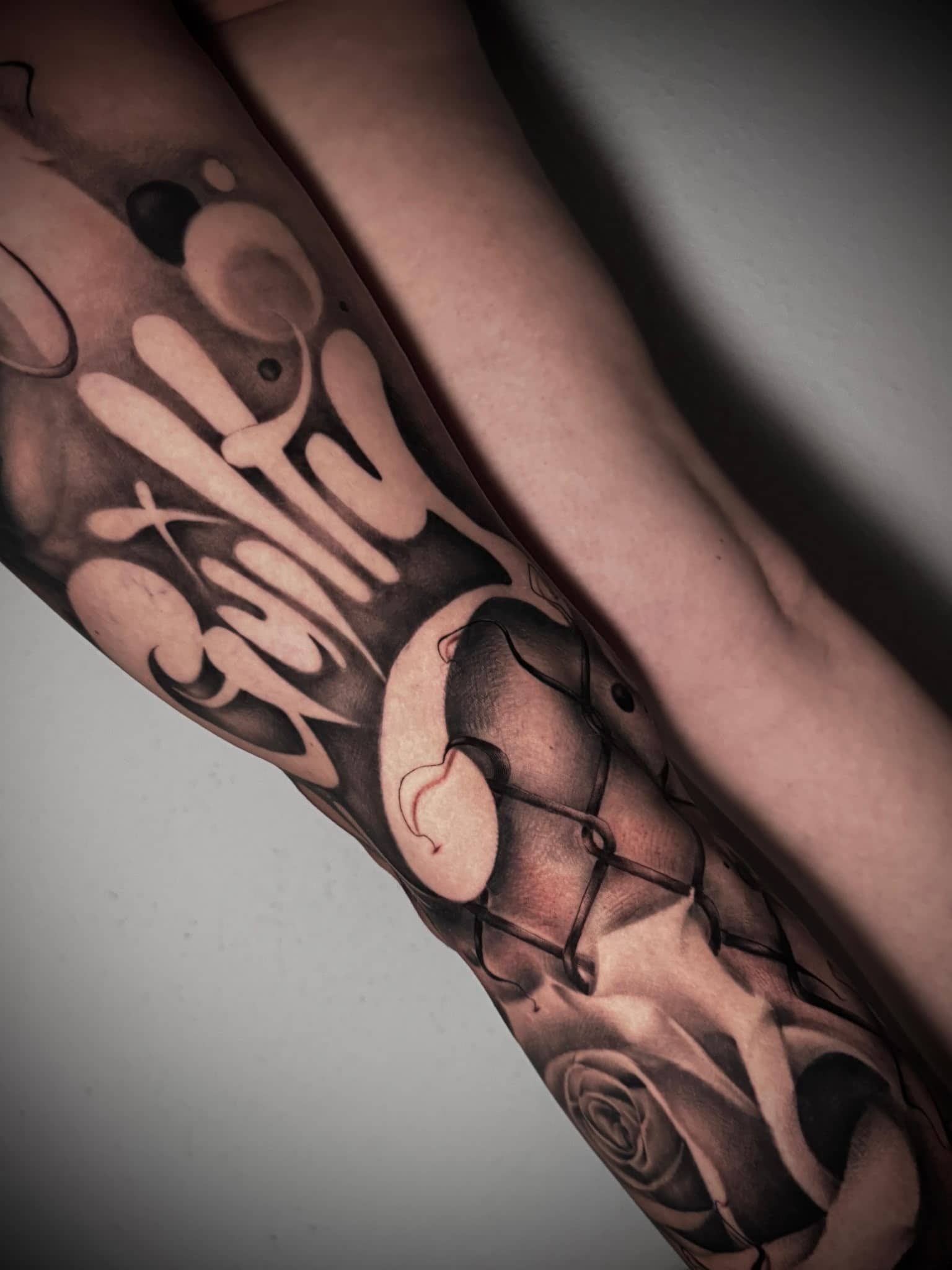 Black and Grey Kalligrafie-Schriftzug Guilty mit Rose und Gesicht am Unterarm