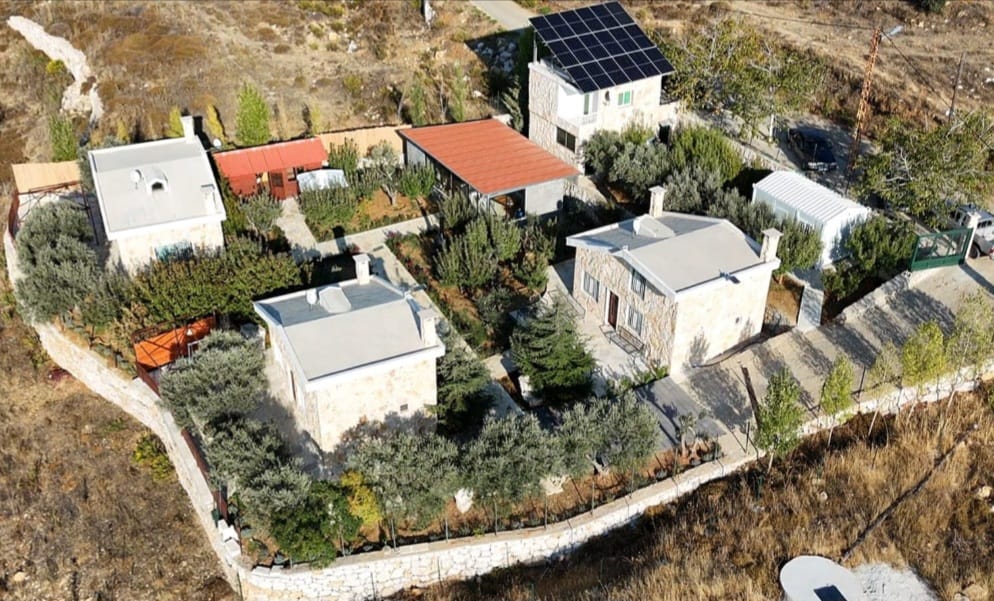Aerial drone view of the Montavi Village compound — stone bungalows, gardens, solar panels