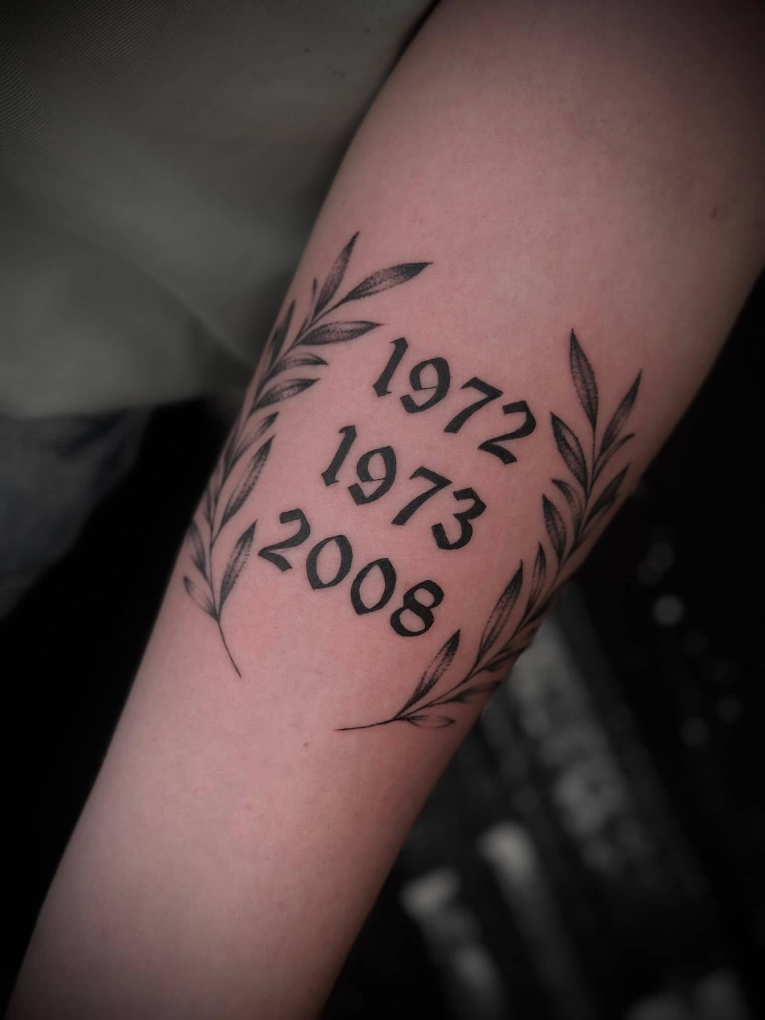 Blackwork Jahreszeiten-Daten 1972 1973 2008 mit Olivenzweigen am Unterarm