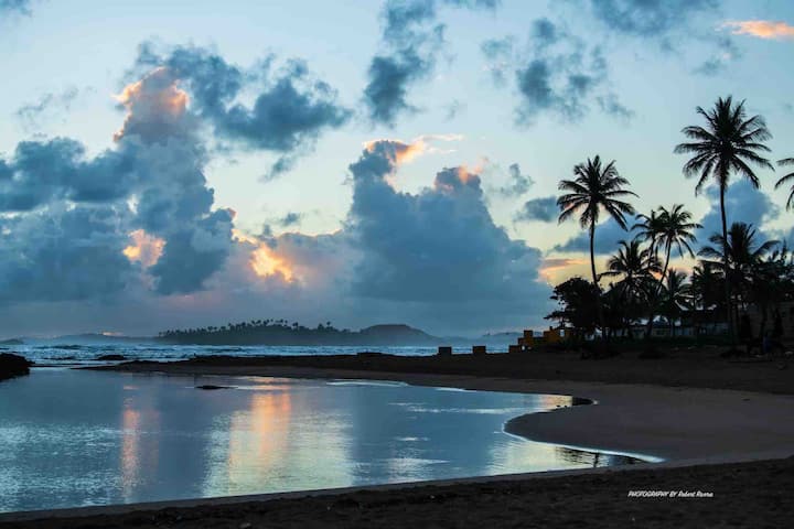 Dusk beach view with palm silhouettes and glowing clouds at Puerto Nuevo
