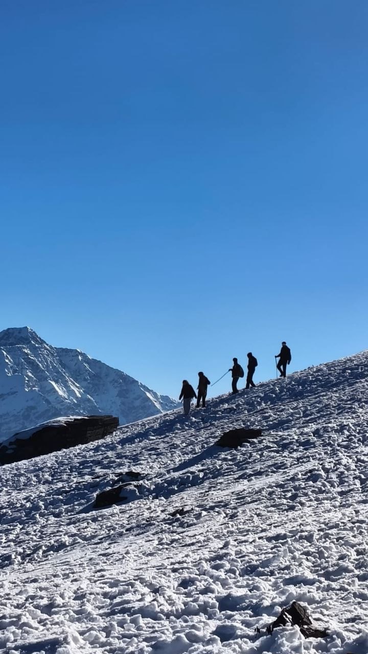 Trekkers on a snowy Himalayan mountain with blue sky