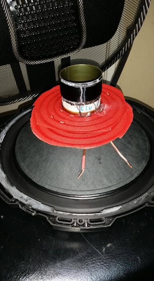 Close-up of a subwoofer voice coil and red suspension on a speaker cone