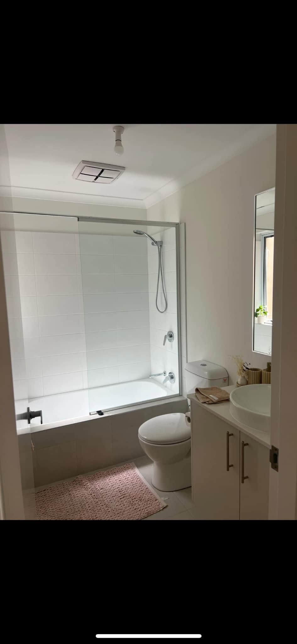 Clean white bathroom with bath shower combo, vanity and freshly painted walls