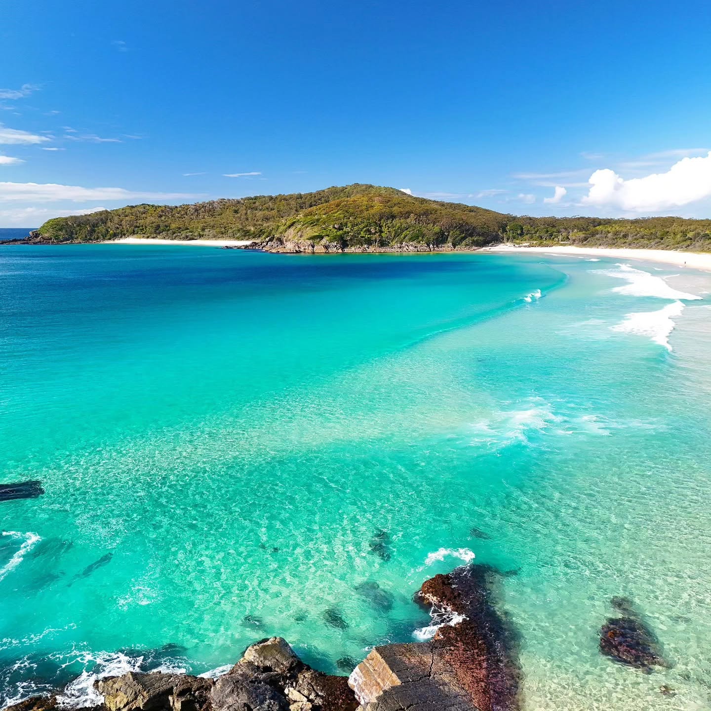 Wide aerial view of a coastal headland and beach along the Mid North Coast