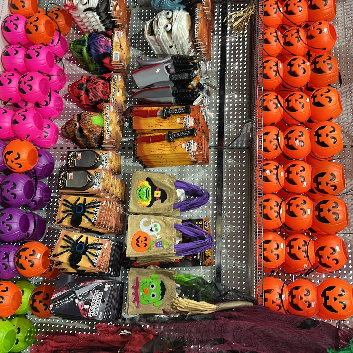 Colourful pumpkin-face Halloween buckets and party bags filling store pegboards