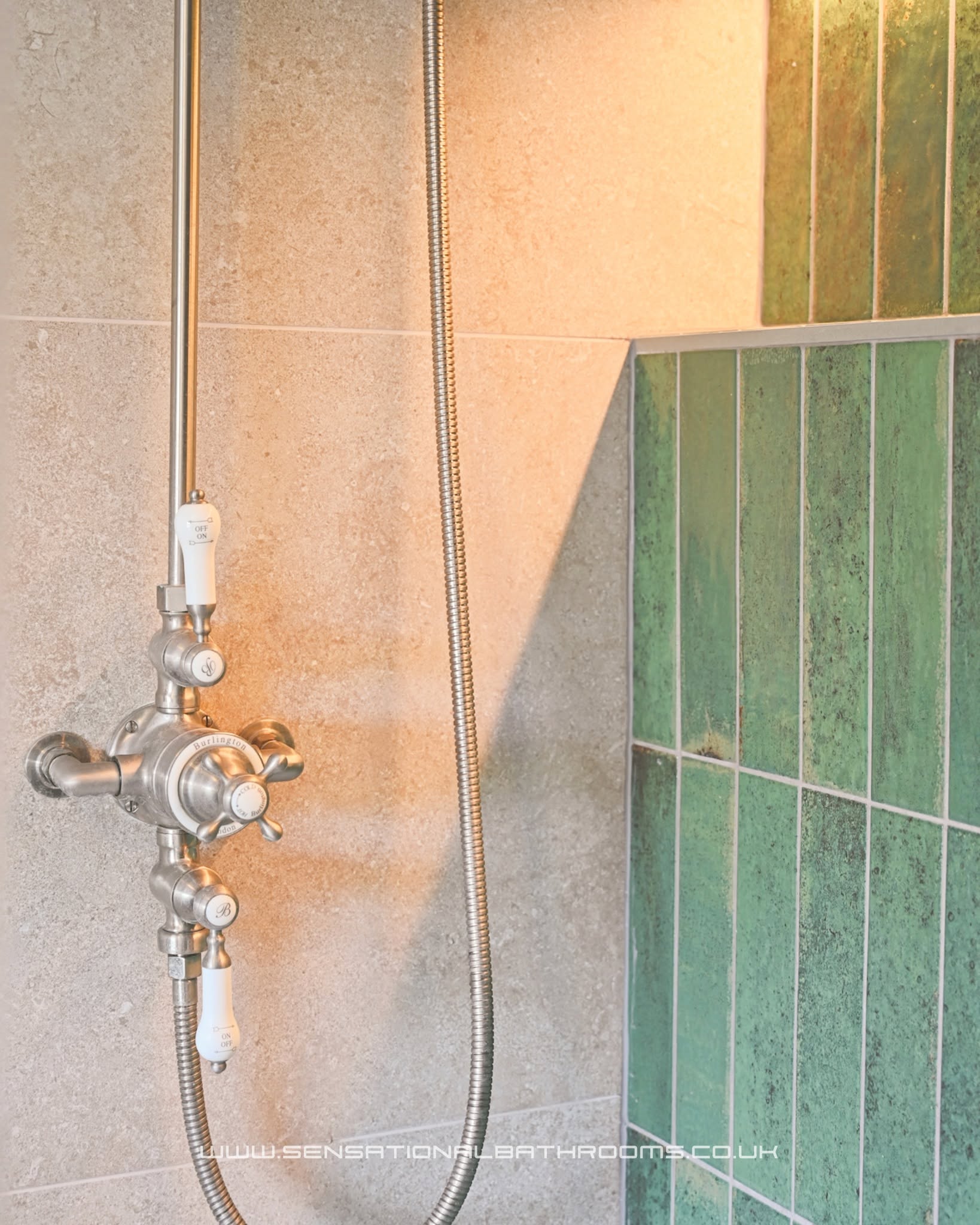 Classic brushed nickel shower valve with cross handles against stone-look tiles and green tiles