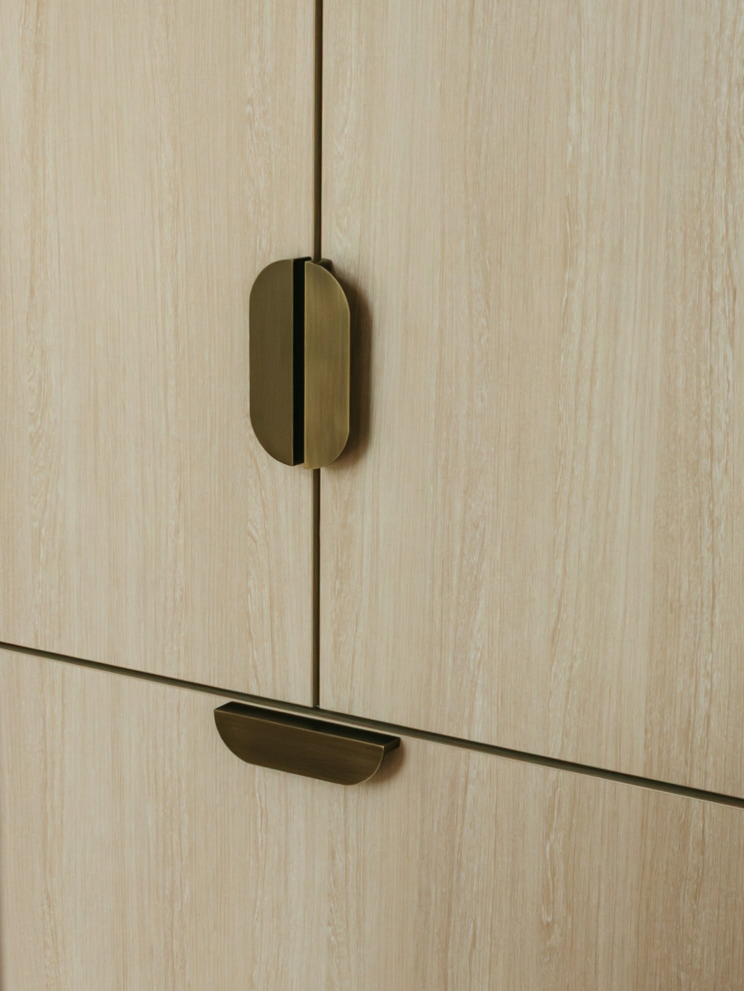 Close-up of a brass wardrobe door handle set into timber cabinetry