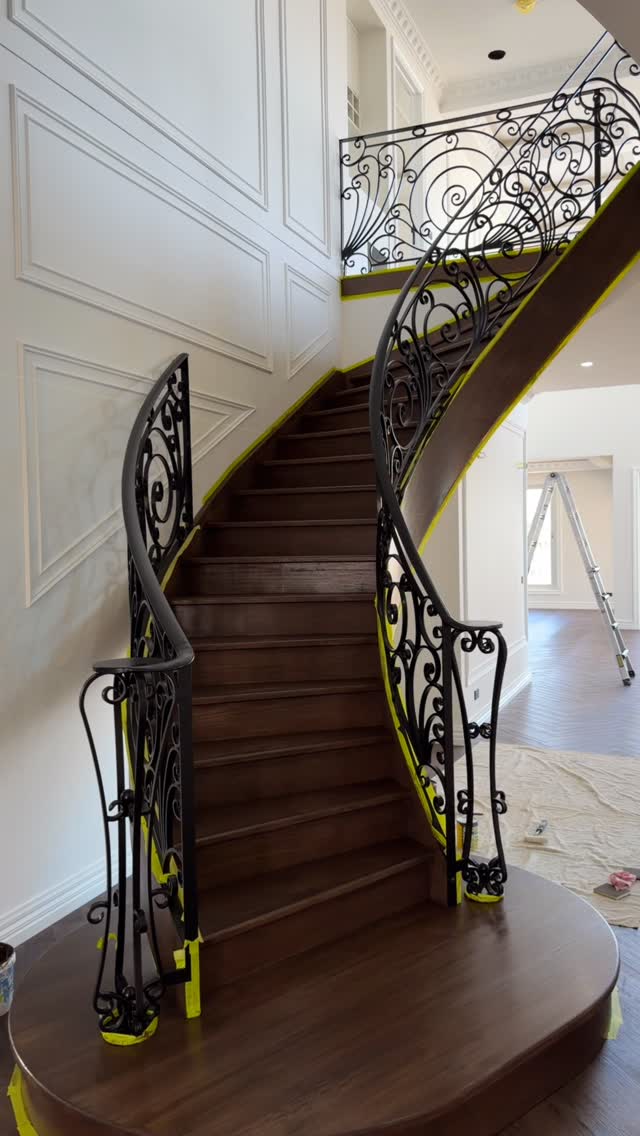 Grand staircase with ornate iron railing against freshly painted white wainscoting walls