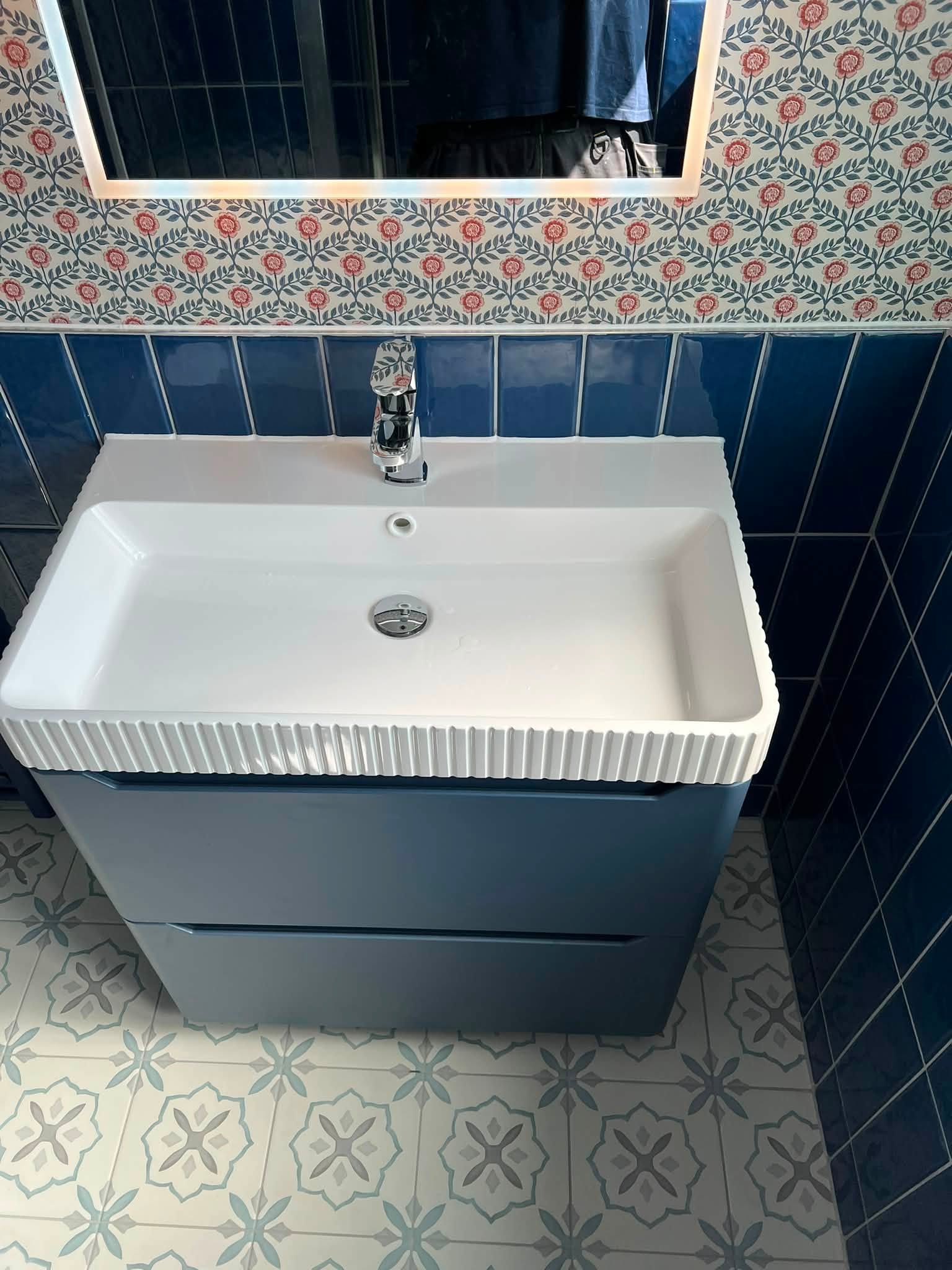 Fluted white sink basin on blue cabinet with chrome tapware
