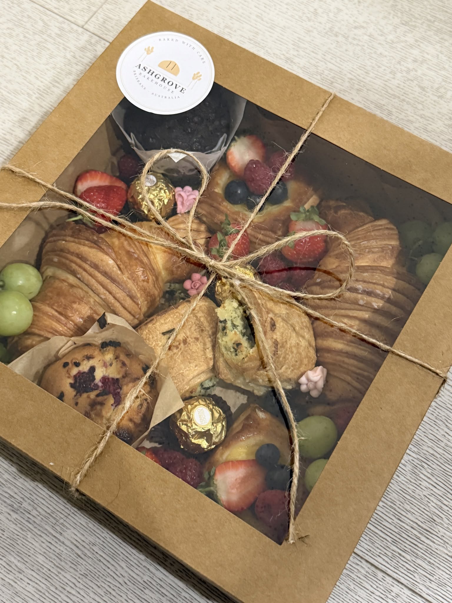 Ashgrove Bakehouse gift box tied with twine, filled with croissants, muffins and fresh fruit