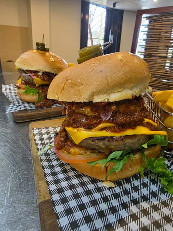 Close-up of a loaded pub burger with cheese and chips at The Yardz Hotel