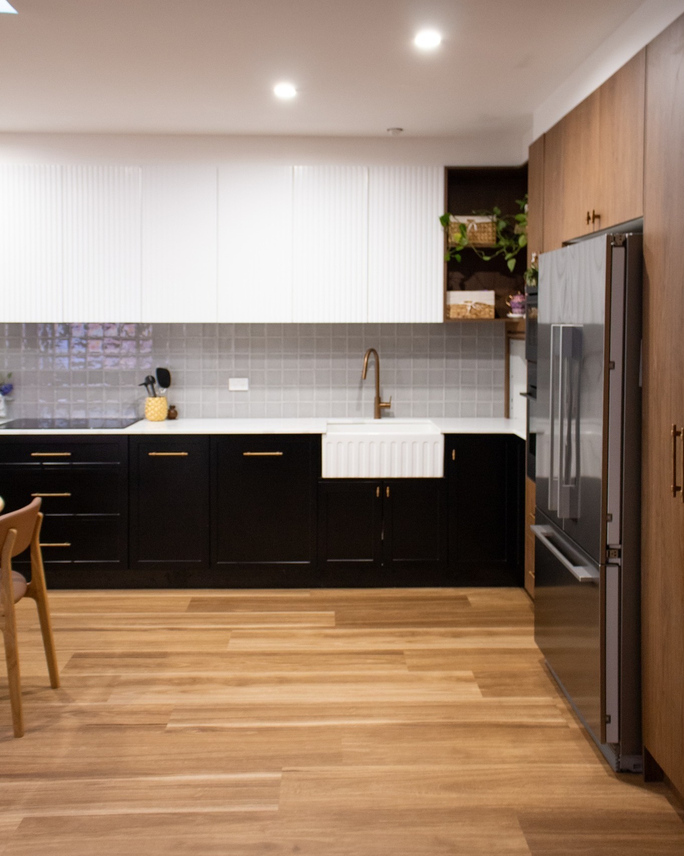 White kitchen joinery with island bench, integrated appliances and timber bar stools