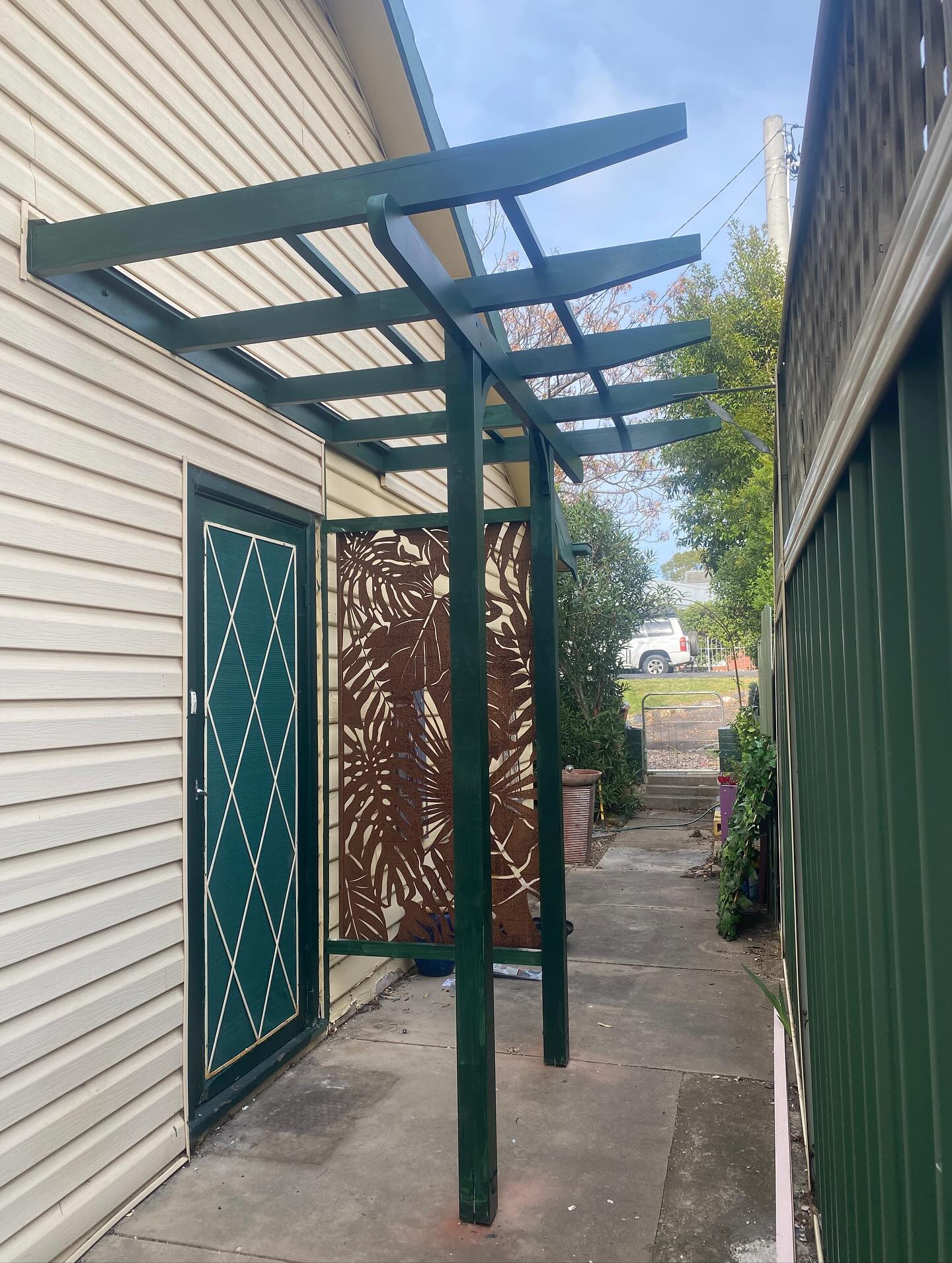 Green steel pergola and decorative screen door installation