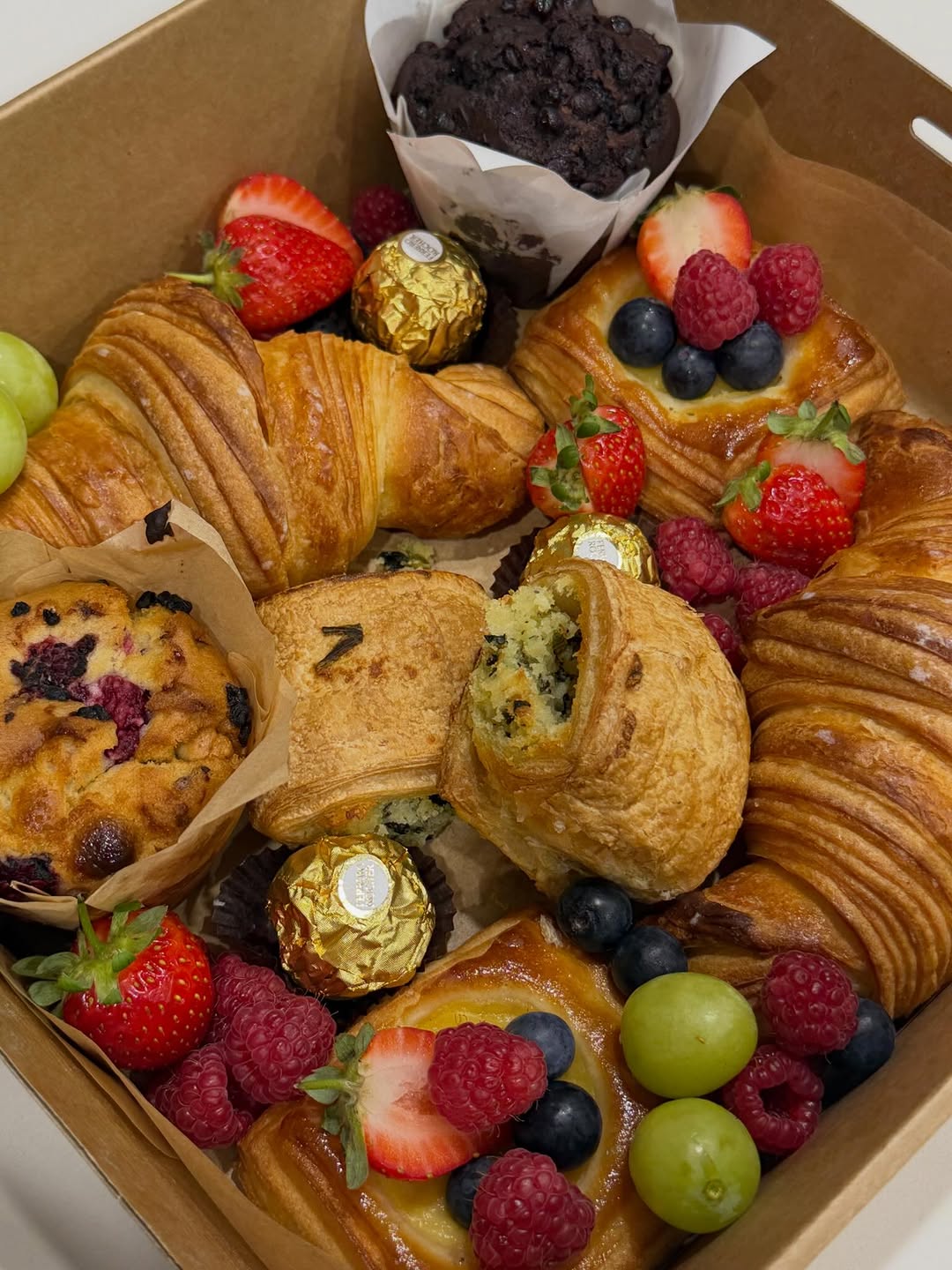 Kraft pastry box with croissants, filled pastry, blueberry muffin and mixed berries