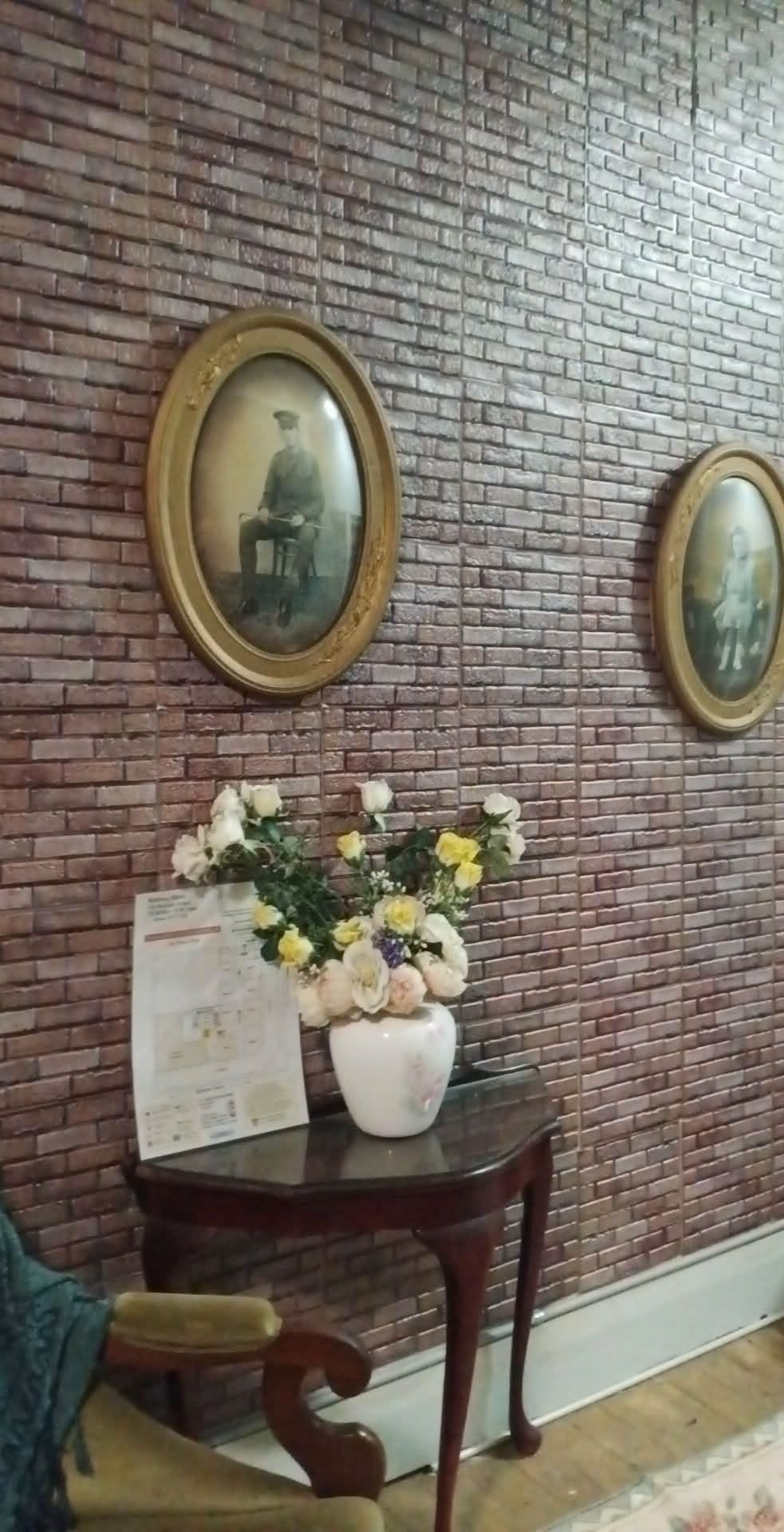Railway Hotel Kandos interior — rustic brick wall with antique oval portrait frames and a flower vase on a timber console table