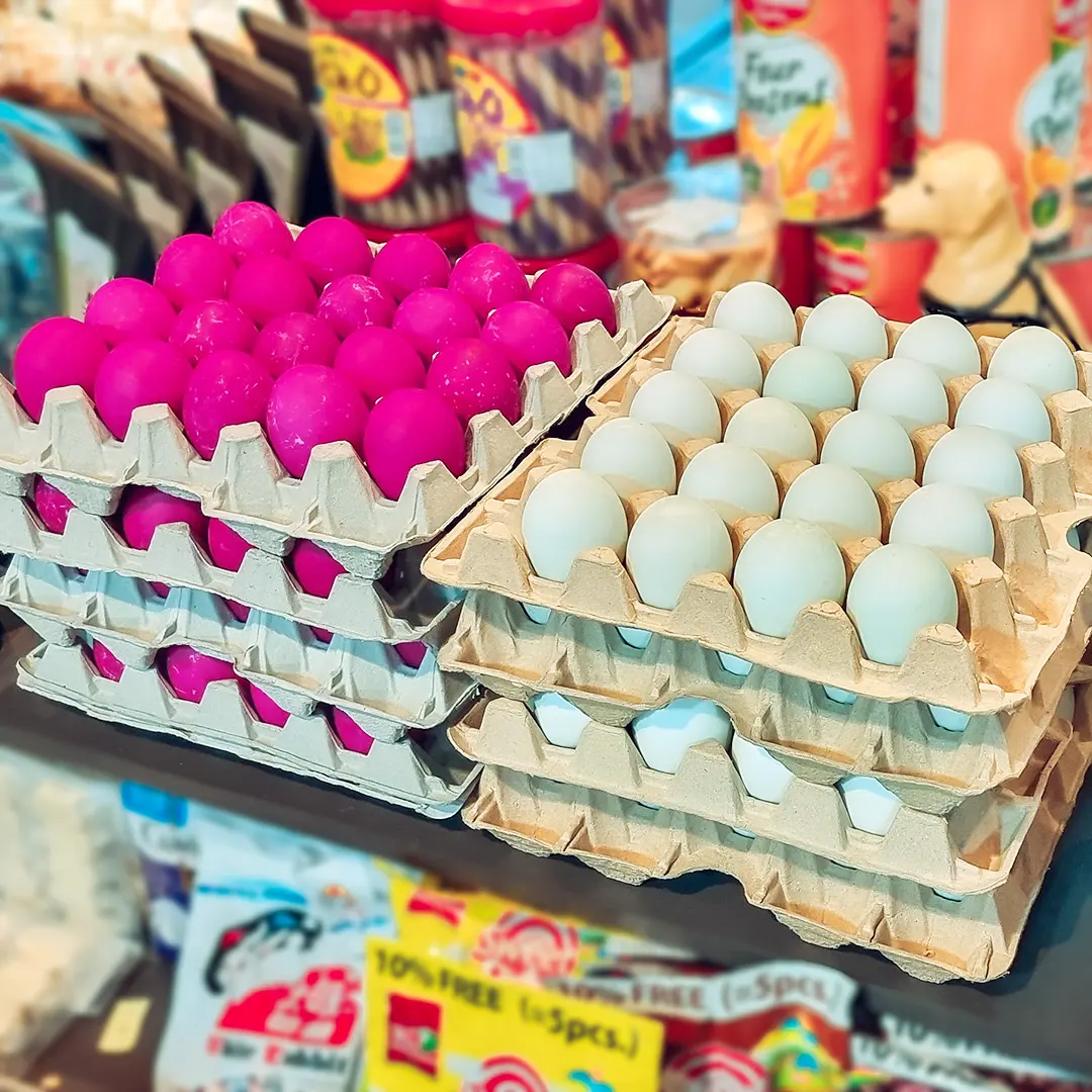 Trays of pink and white salted eggs on a shop shelf