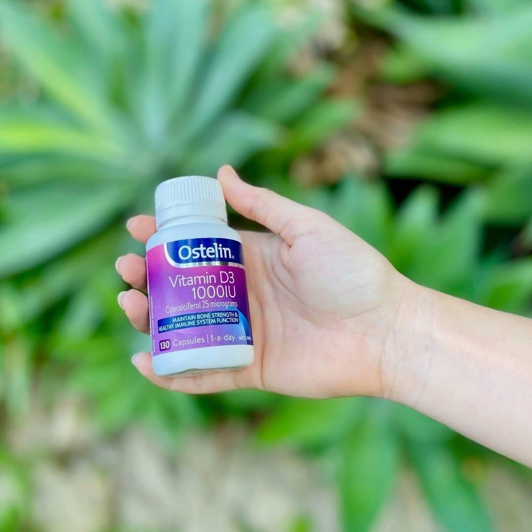 Bottle of vitamin D capsules held in front of green garden plants