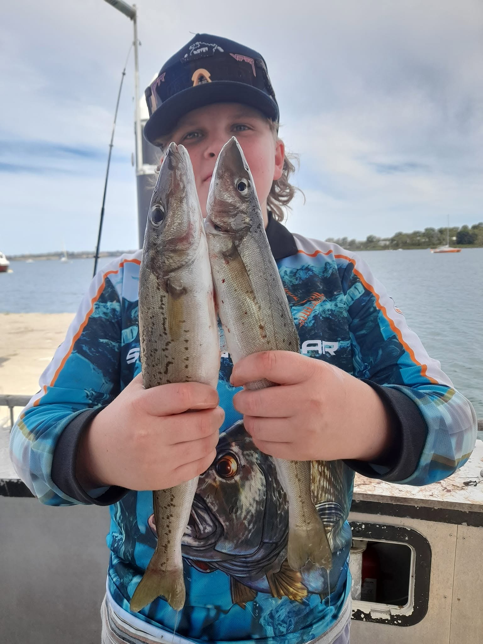 Young angler proudly holding two large whiting caught on the charter