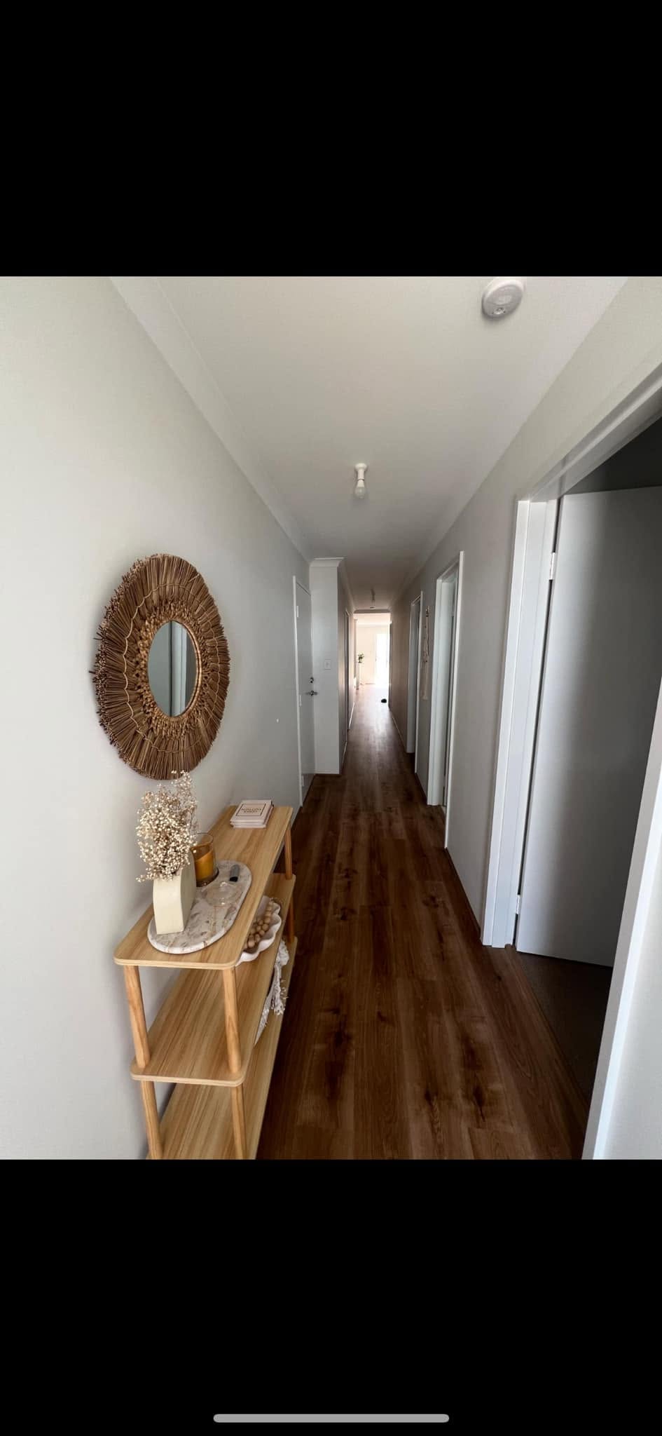 Freshly painted hallway with warm timber floors and decorative mirror — exterior painting result