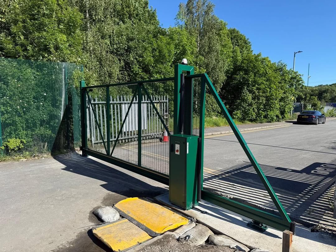 Green steel sliding security gate installed at an industrial site