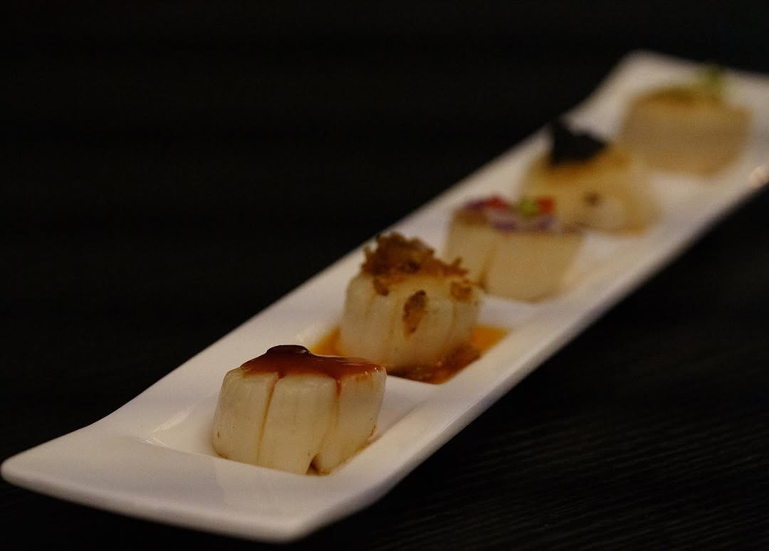 Elegantly plated steamed scallop pieces on a long white platter