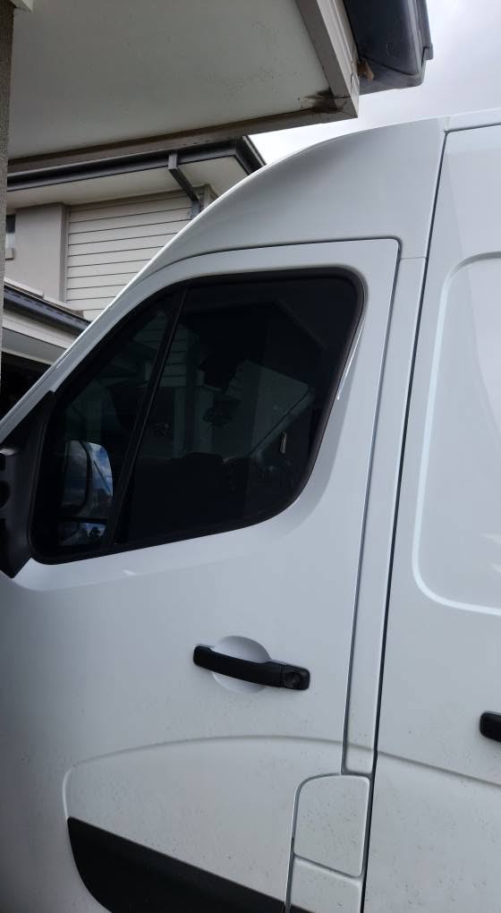 Close-up of a professionally tinted vehicle window on a white van