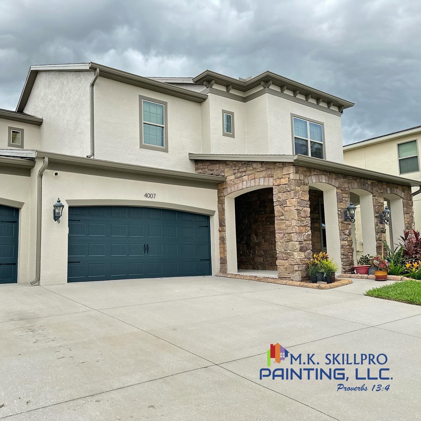 Painted stucco home exterior with teal garage doors