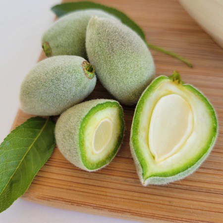 Fresh green almonds on a wooden board