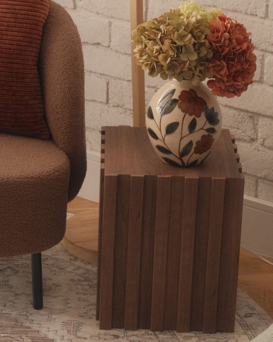 Wooden side table with a ceramic floral vase and dried hydrangeas, representing home decor products