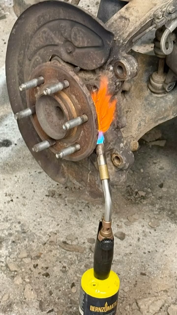 Close-up of a mechanic using a torch during a brake and suspension repair