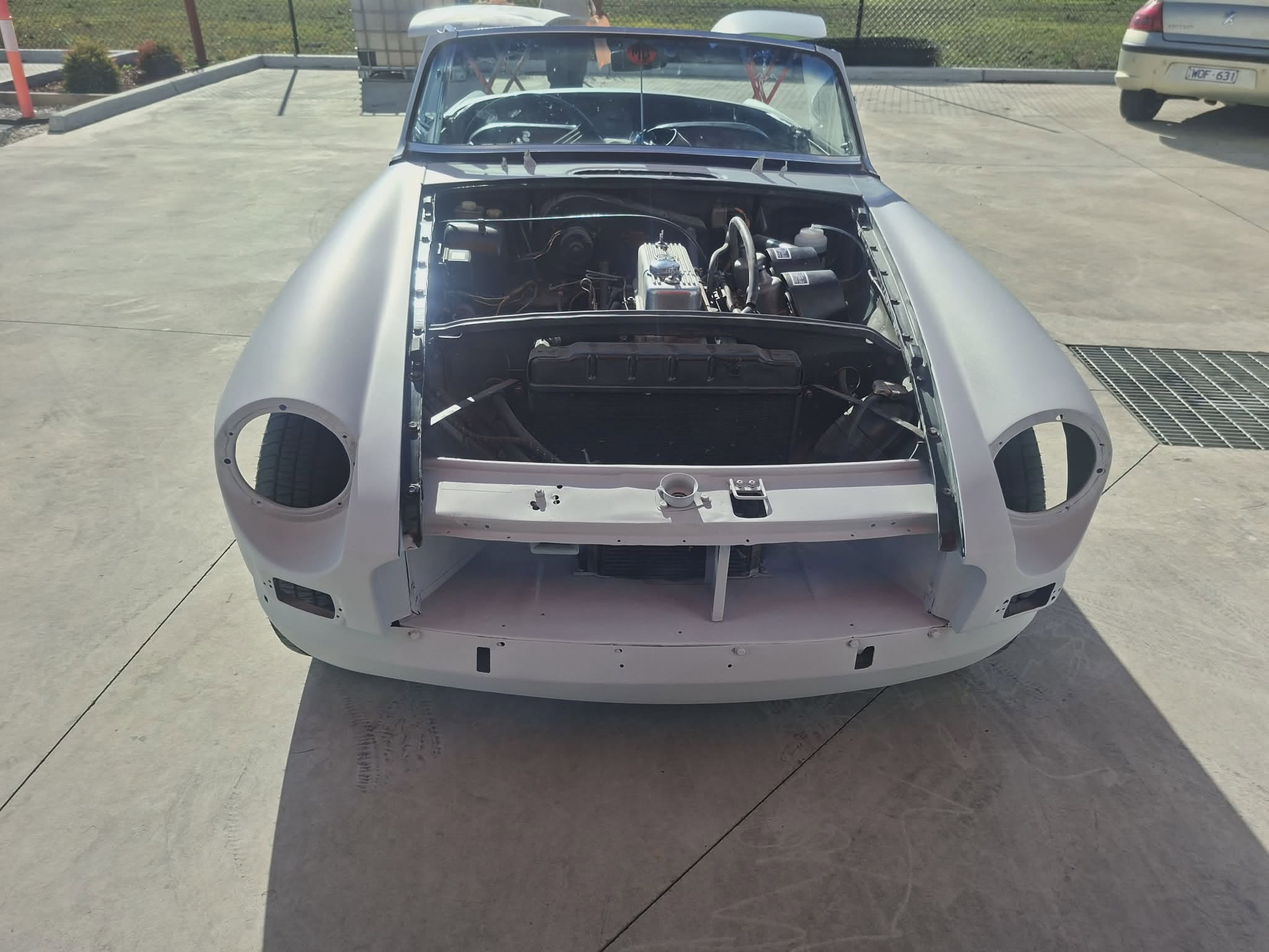 Classic MGB roadster stripped to bare shell in grey primer — full restoration at April Motors