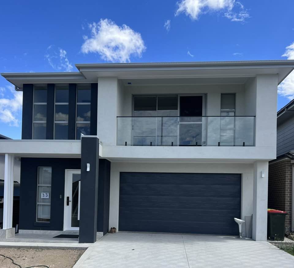 Navy and white double-storey home with a glass-balustrade balcony and double garage