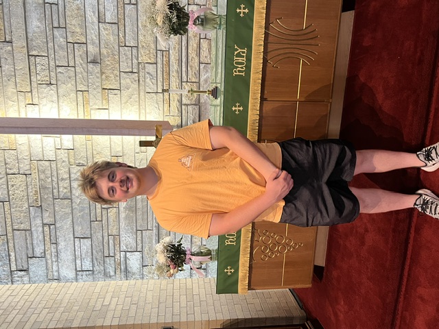 A teenager standing in front of the altar after a youth ministry milestone