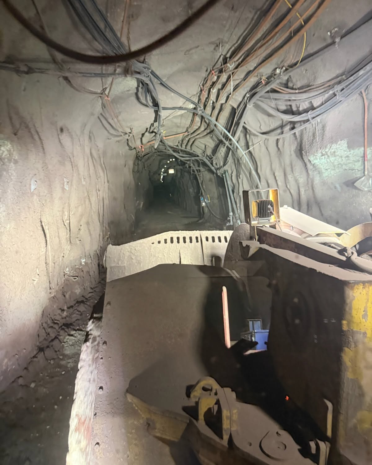 Underground mine tunnel with heavy machinery and cabling — fixed-plant and stationary engine environment